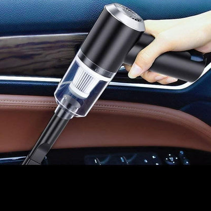 Hand holding a black and silver car vacuum cleaner inside a vehicle.