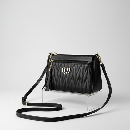Black quilted handbag with a heart-shaped clasp on a light background